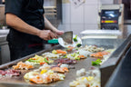 Koch bereitet frische Zutaten auf der heißen Grillplatte im Chinakrone Restaurant zu