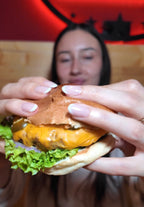 Frau hält einen frisch zubereiteten Burger im Rn Beef Moers und bereitet sich darauf vor, ihn zu genießen