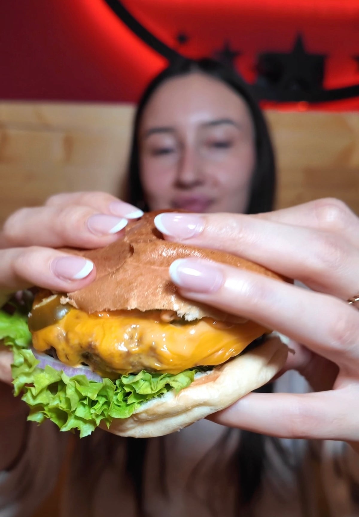 Frau hält einen frisch zubereiteten Burger im Rn Beef Moers und bereitet sich darauf vor, ihn zu genießen