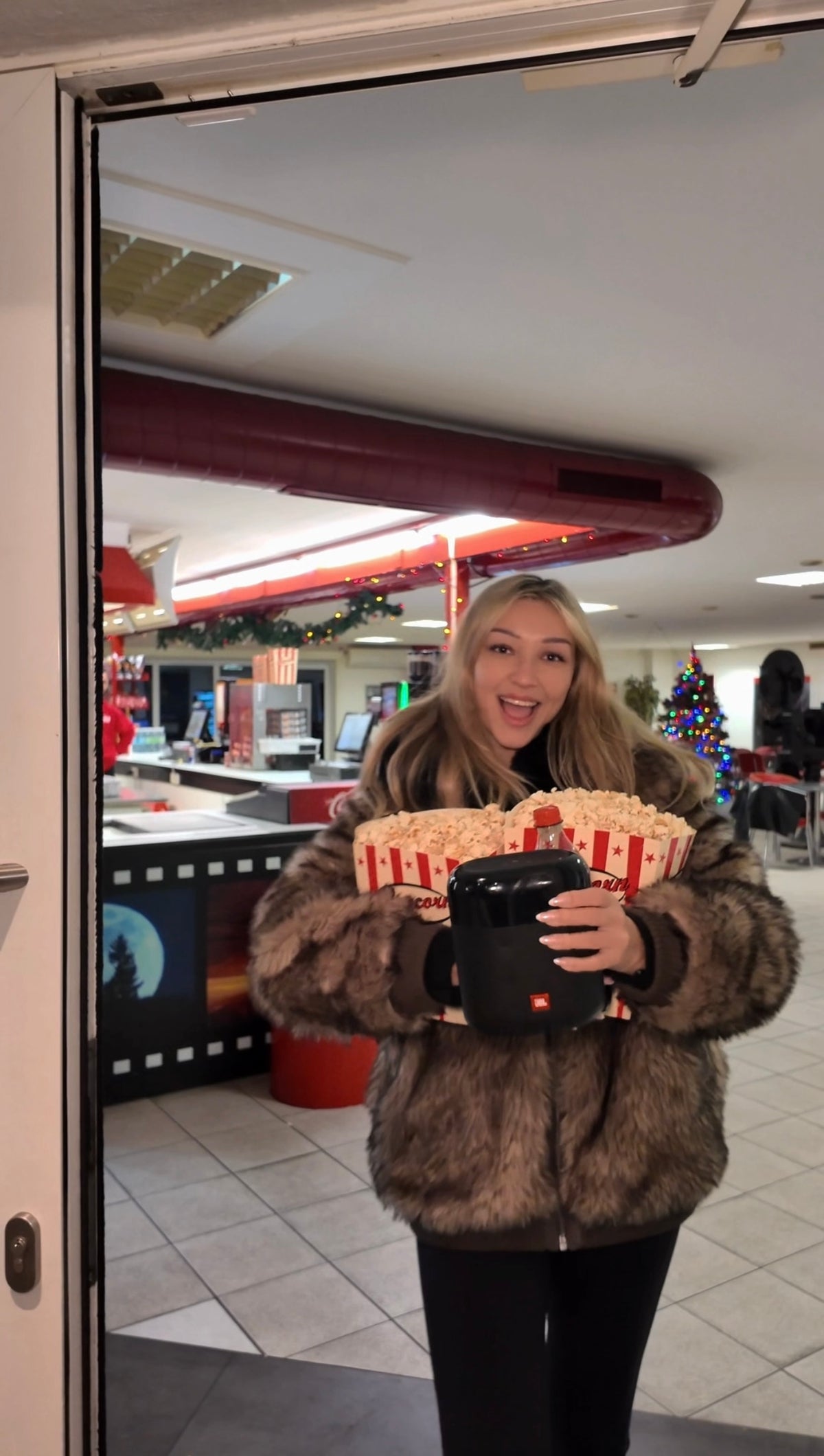 Frau lächelt und hält eine große Tüte Popcorn im Autokino Essen, vor dem Kioskbereich