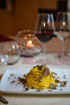 Tagliolini mit frischem Trüffel auf weißem Teller, serviert mit Rotwein im edlen Ambiente