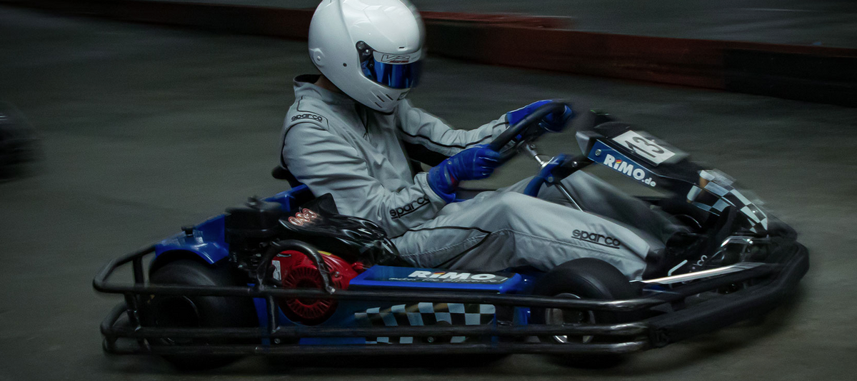 Rennfahrer mit Helm und Overall im Go-Kart bei Highway Kart Racing Dortmund