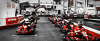 Mehrere Fahrer in roten Karts beim Start auf der Indoorbahn von Highway Kart Racing Dortmund
