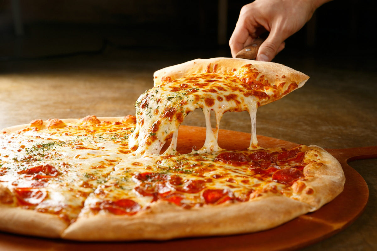 Frisch gebackene Pizza mit Käse und Salami, ein Stück wird mit ziehendem Käse abgehoben