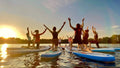 Gruppe beim Stand-up-Pilates auf dem Halterner See bei Sonnenuntergang mit Paddel
