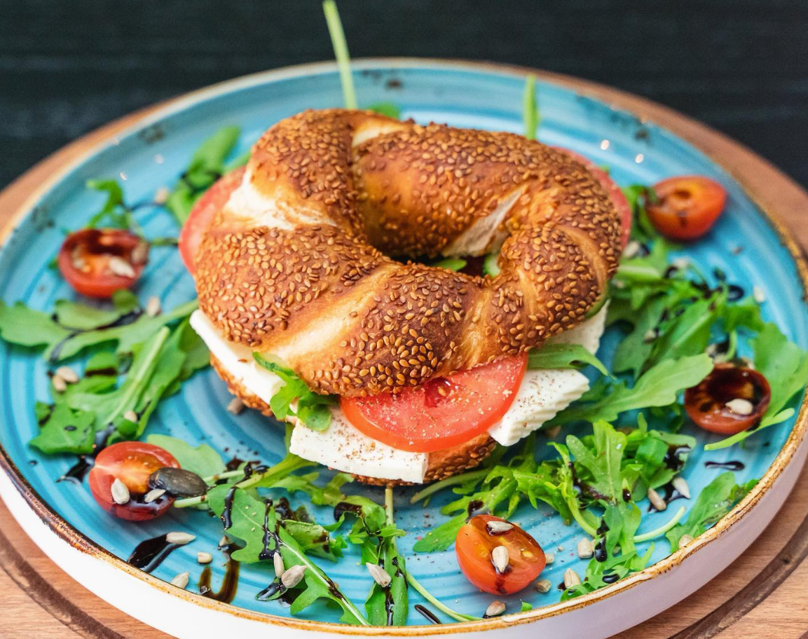 Frisch belegter Simit mit Käse, Tomaten und Rucola auf dekorativem Frühstücksteller bei Meeting Die Brunchery Dortmund