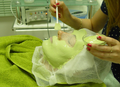 Frau bei Gesichtsbehandlung mit grüner Pflegemaske im Beauty Center Berlin