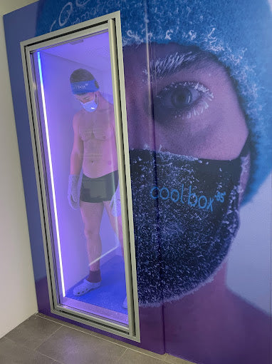 Mann in Shorts und Mütze steht in der beleuchteten Kryokammer der Coolbox Essen