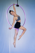 Frau in sportlichem Outfit zeigt eine elegante Pose im Aerial Hoop bei einer Luftakrobatik-Performance