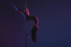 Frau beim Pole Dance in eleganter Pose unter dramatischer Bühnenbeleuchtung